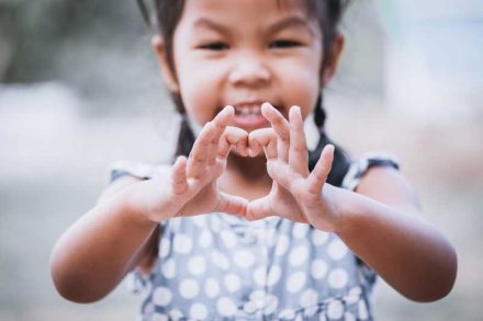 A Cambodian girl making a heart symbol with her hands