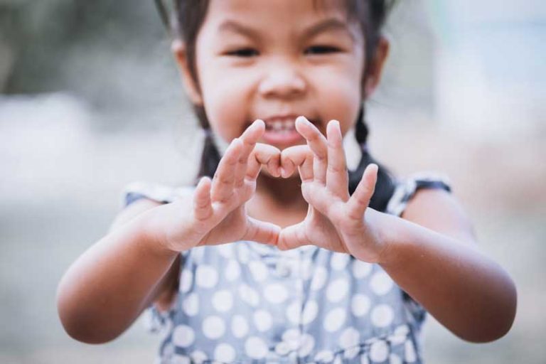 A Cambodian girl making a heart symbol with her hands